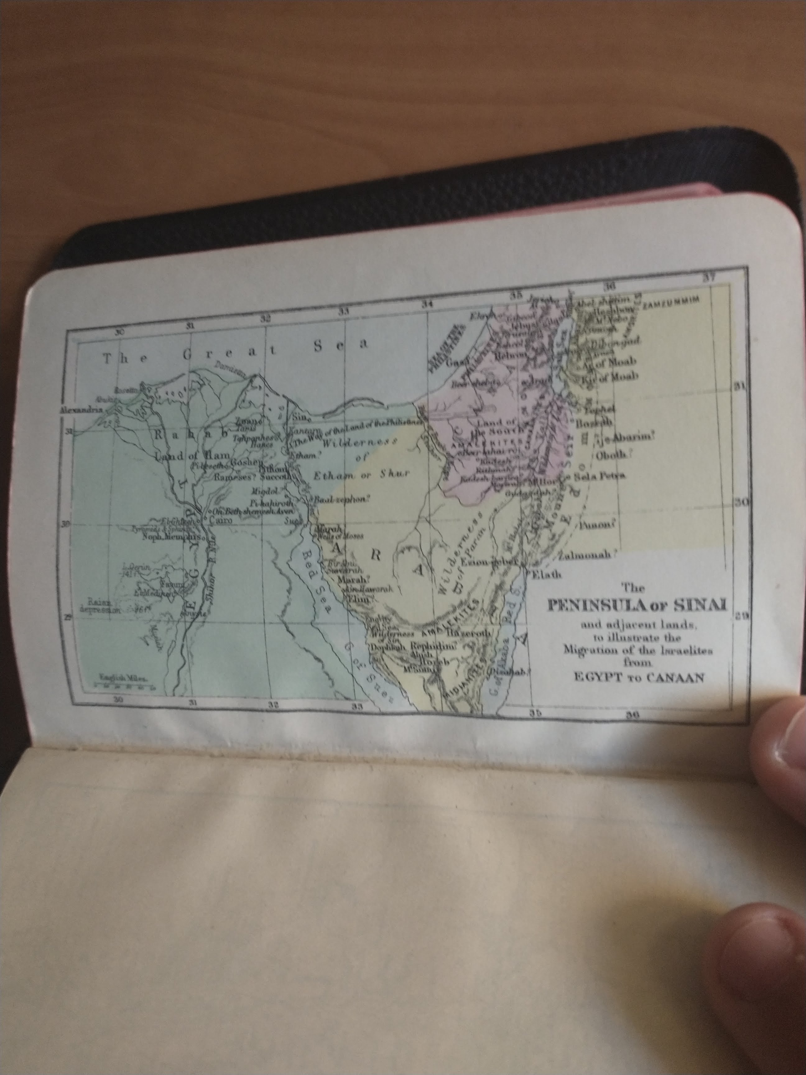 The Bible is open to the last page. Unlike the previous pages, it is open horizontally. It shows a colored map of modern-day Egypt, Israel, and surrounding regions, centered on the Sinai Peninsula. The title of the map reads "The Peninsula Of Sinai and adjacent lands, to illustrate the Migration of the Israelites from EGYPT to CANAAN". The picture is slightly blurry, making it hard to read all of the text detailing various cities and points of interest on the map. The map appears to list both where modern-day cities are located, as well as where different groups of people are thought to have lived at some point; for example, the Nile Delta is labeled with "Land of Ham". The Mediterranean Sea is labeled as "The Great Sea". There are latitude lines labeled from 28 to 32, and longitude lines from 29 to 37.